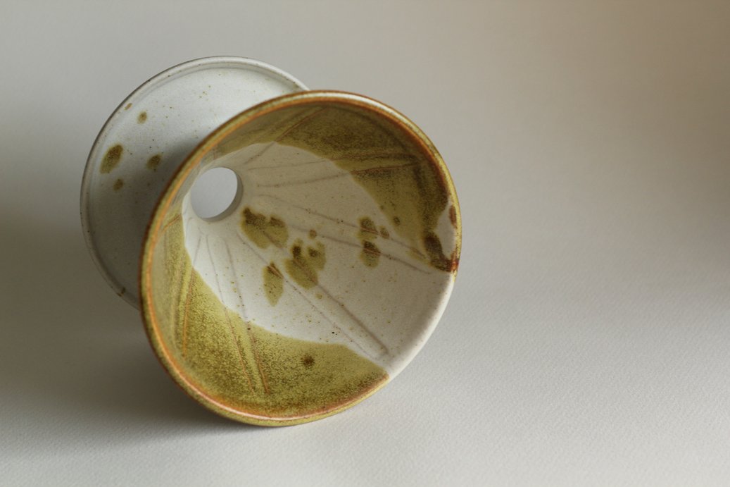 V60-style coffee dripper in white and mossy green glaze.